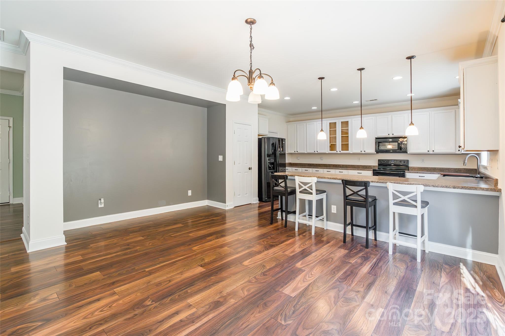 9312 Seamill Road Charlotte, NC 28278 - Photo 11 of 30 a open kitchen with stainless steel appliances granite countertop a stove top oven a refrigerator and a dining table with wooden floor