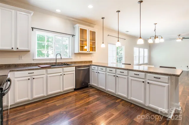 a kitchen with stainless steel appliances granite countertop a sink a window and white cabinets