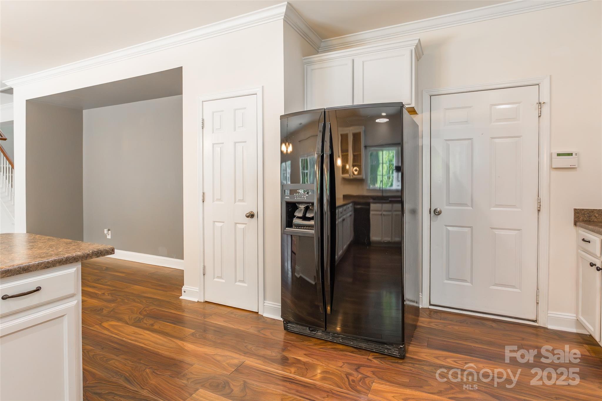9312 Seamill Road Charlotte, NC 28278 - Photo 14 of 30 a view of a refrigerator in kitchen and an empty room in wooden floor