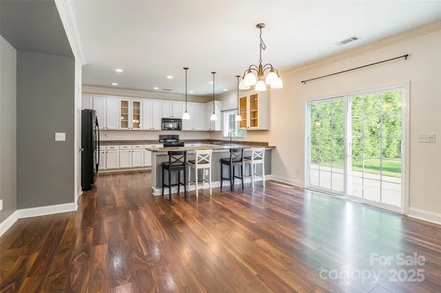 a view of a dining room and livingroom with furniture wooden floor a chandelier
