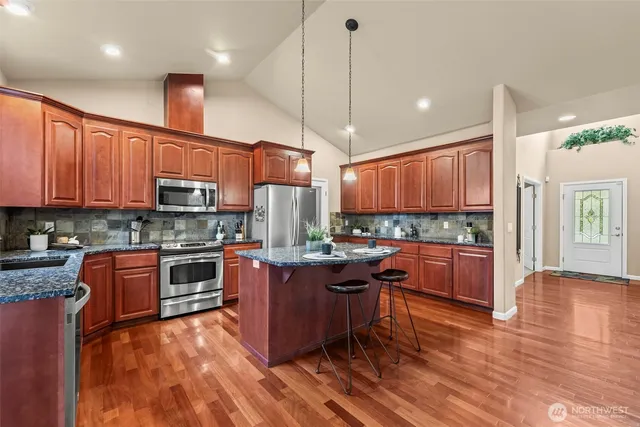a kitchen with stainless steel appliances granite countertop wooden floors stove top oven and refrigerator