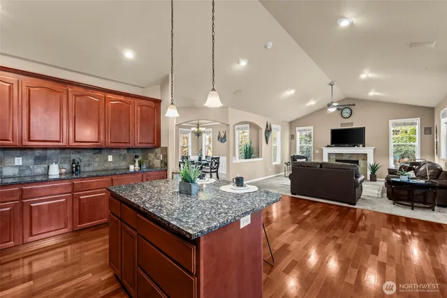 a kitchen with stainless steel appliances granite countertop a stove top oven a sink dishwasher a dining table and chairs with wooden floor