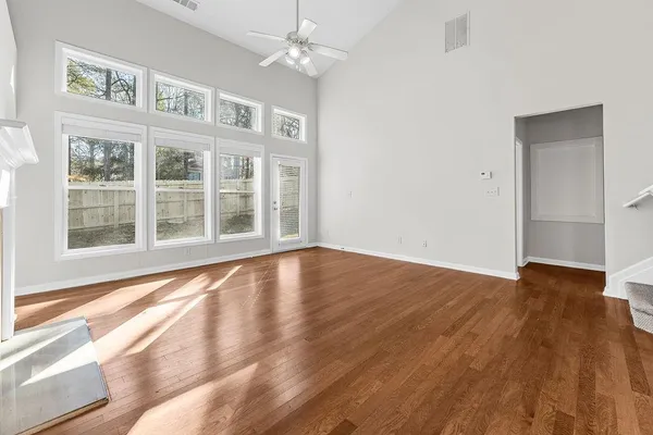 a view of an empty room with wooden floor and a window