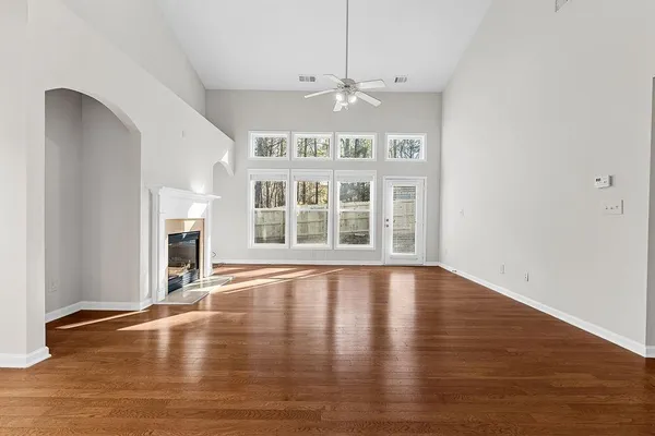 a view of an empty room with wooden floor and a window