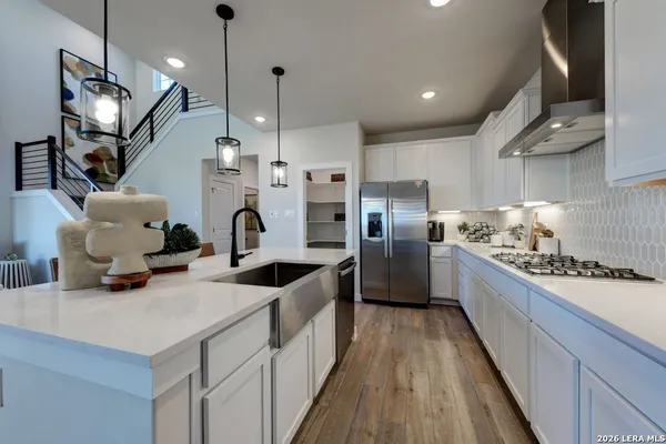 a kitchen with refrigerator a stove and wooden floor