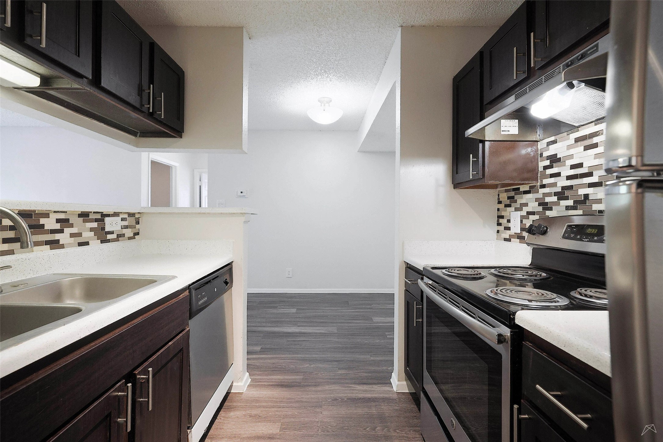 6808 South I-35 Frontage Road, Unit 253 Austin, TX 78745 - Photo 11 of 21 Kitchen with tasteful backsplash, stainless steel appliances, light countertops, a textured ceiling, and dark wood finished floors