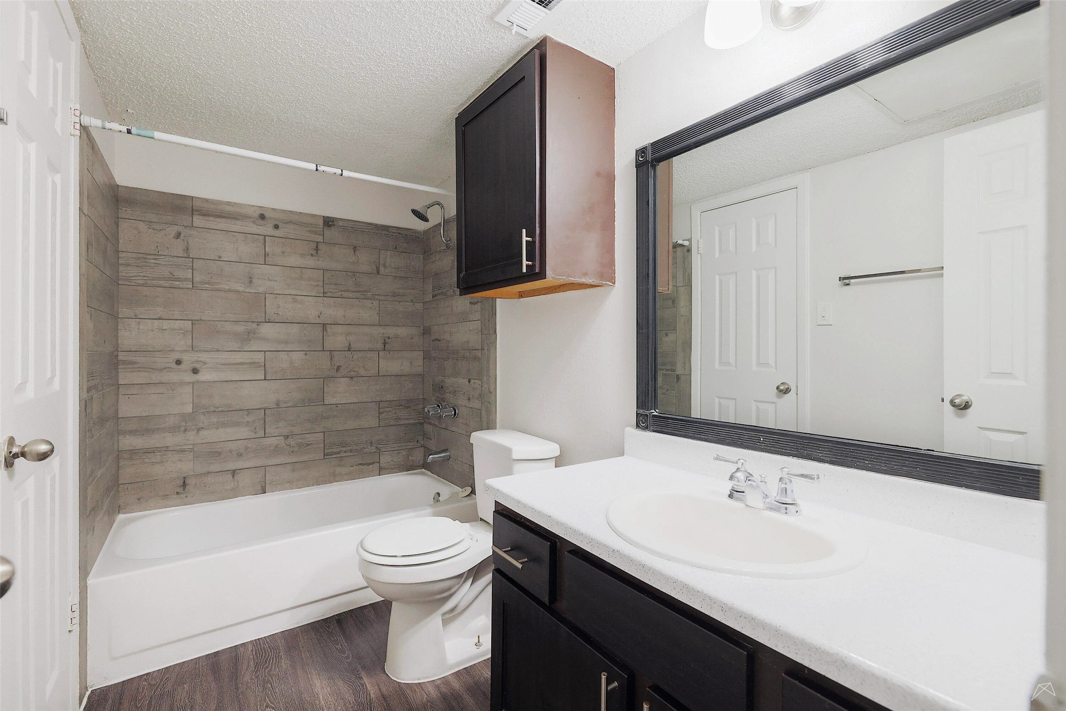 6808 South I-35 Frontage Road, Unit 253 Austin, TX 78745 - Photo 17 of 21 Bathroom featuring vanity, shower combination, a textured ceiling, and dark wood finished floors