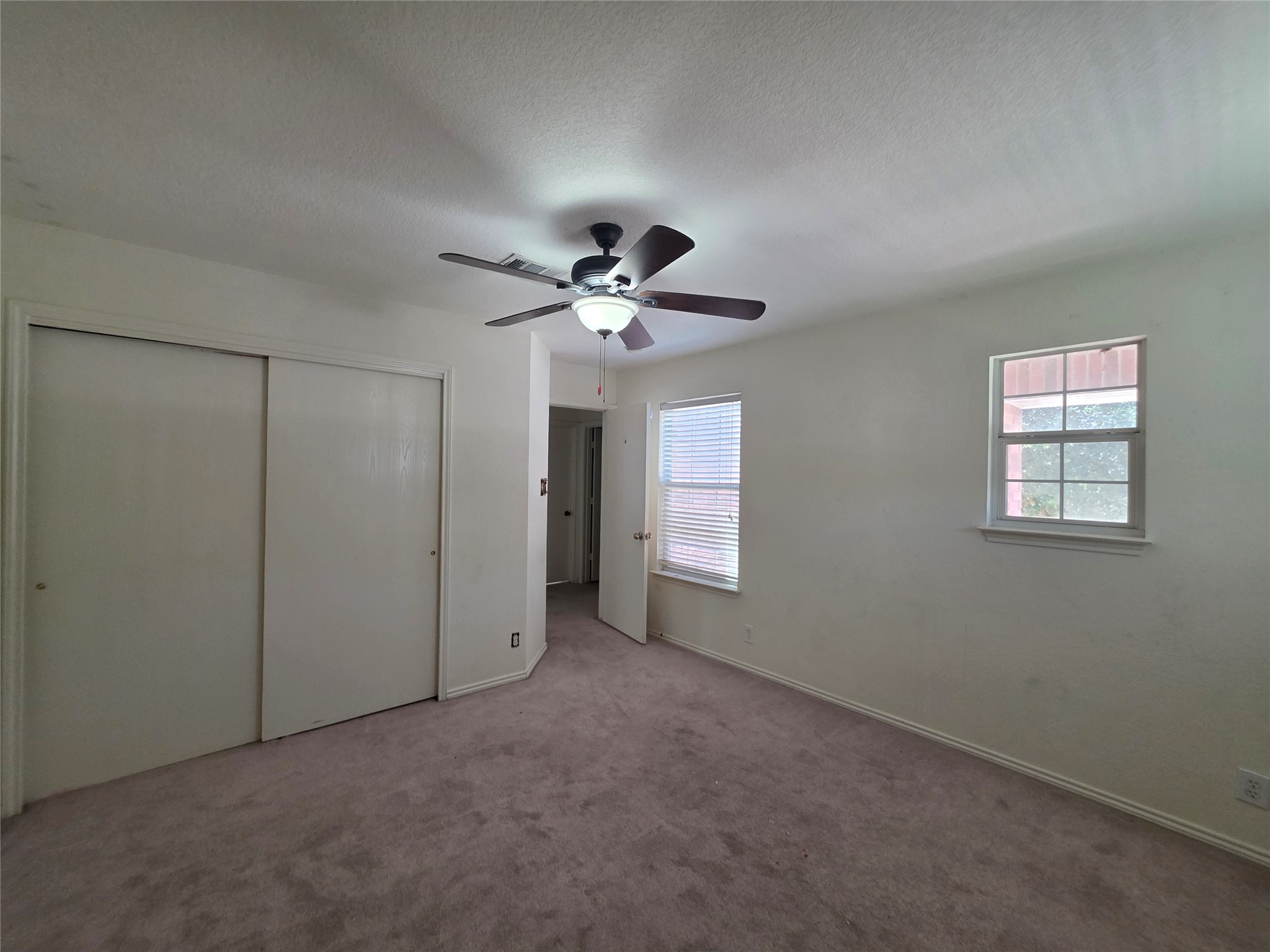 189 Ruidoso Road Kyle, TX 78640 - Photo 17 of 31 A comfortable bedroom with soft carpet, a pair of windows, and a ceiling fan for year-round comfort.