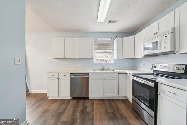 a kitchen with cabinets appliances wooden floor and a window
