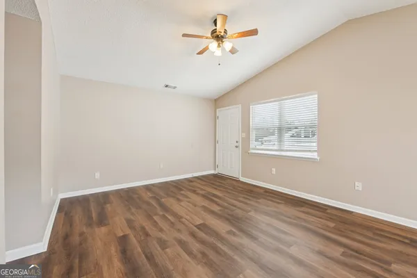 an empty room with windows and fan