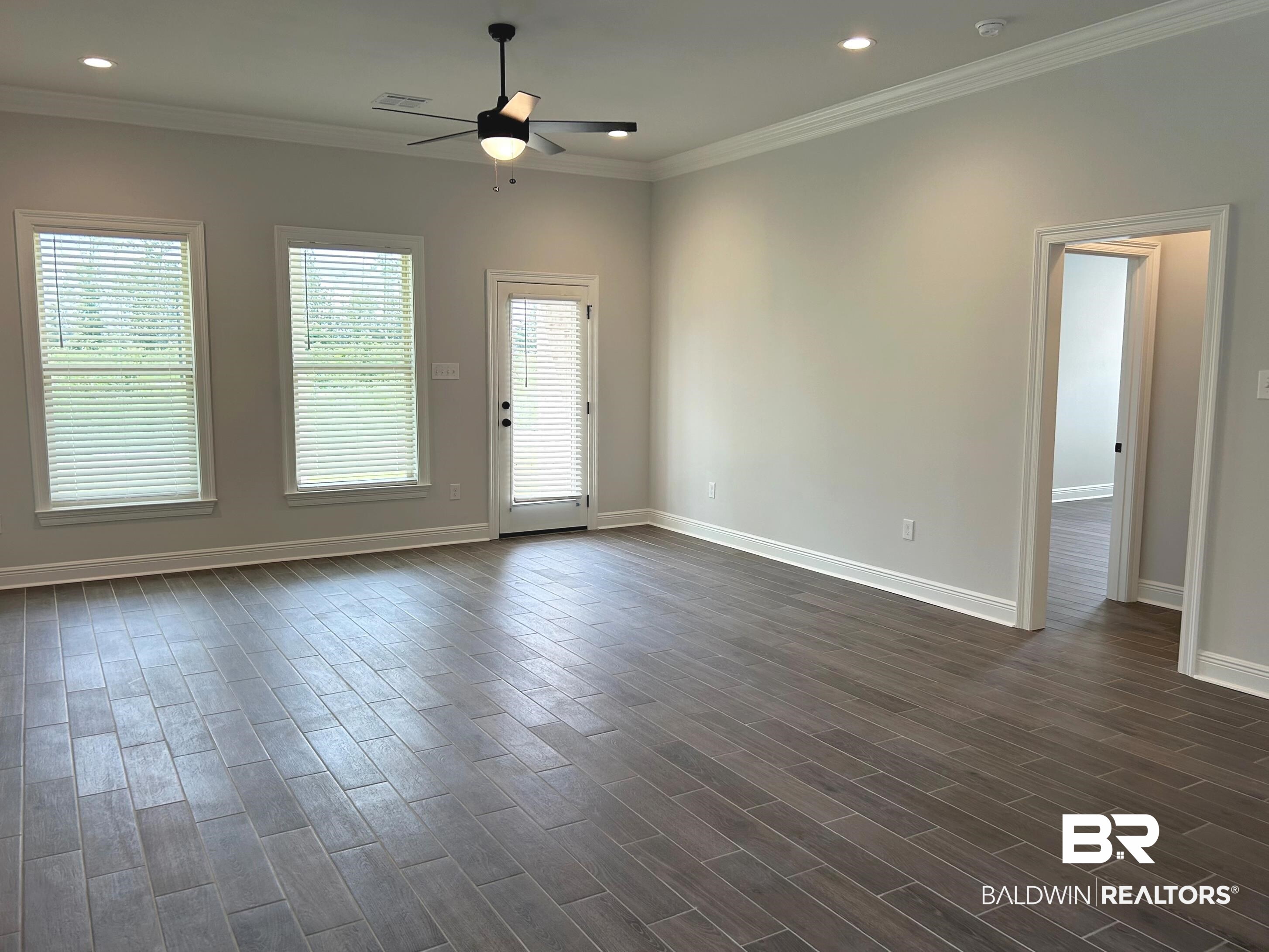 876 Sumter Loop Foley, AL 36535 - Photo 11 of 24 Unfurnished room featuring ornamental molding, a wealth of natural light, ceiling fan, and dark wood-type flooring