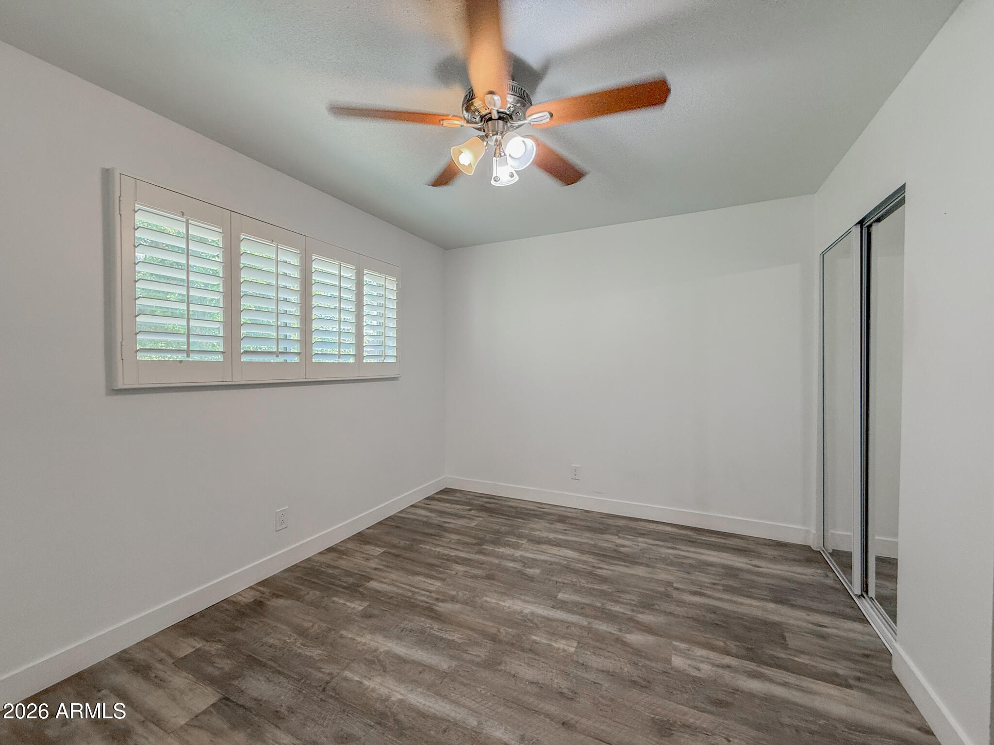 5525 East Thomas Road, Unit B7 Phoenix, AZ 85018 - Photo 9 of 23 a view of an empty room with wooden floor and a window