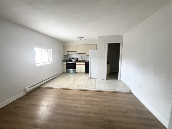 a view of empty room with kitchen and window