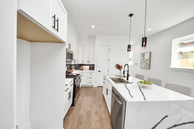 a kitchen with a sink a stove a refrigerator and white cabinets