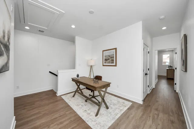 a view of a hallway with wooden floor and a bathroom
