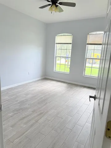 an empty room with windows and fan