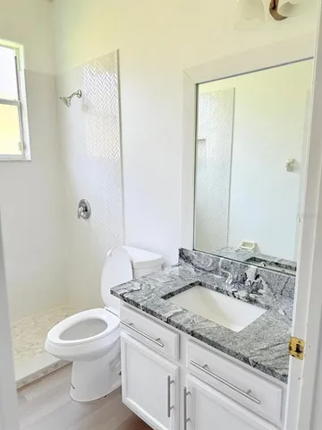 a bathroom with a granite countertop sink toilet and shower