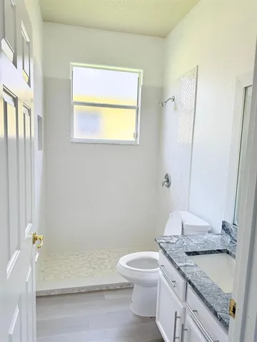 a bathroom with a granite countertop sink toilet and shower
