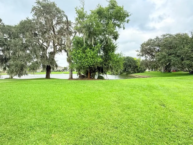 a view of grassy field with benches and trees all around