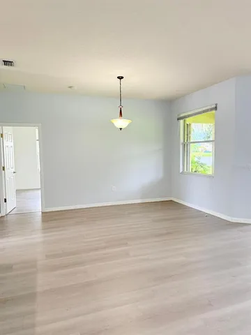 a view of an empty room with window and wooden floor