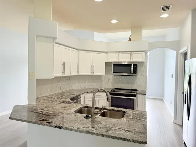 a kitchen with granite countertop a refrigerator and a stove top oven