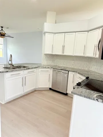 a kitchen with granite countertop white cabinets and white appliances