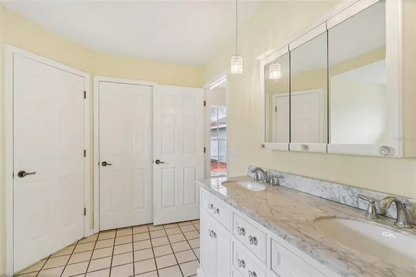 a bathroom with a granite countertop sink two mirror and a shower