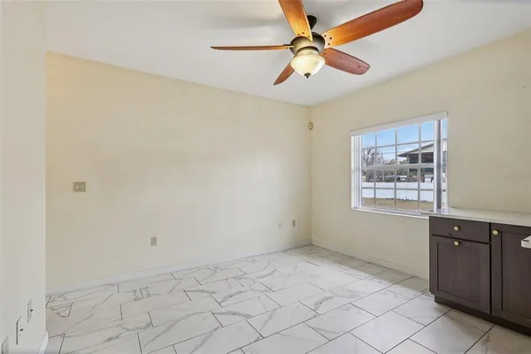 a view of an empty room and window with a fan