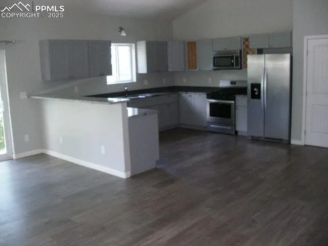 a kitchen with stainless steel appliances granite countertop a sink a stove a refrigerator and wooden floor