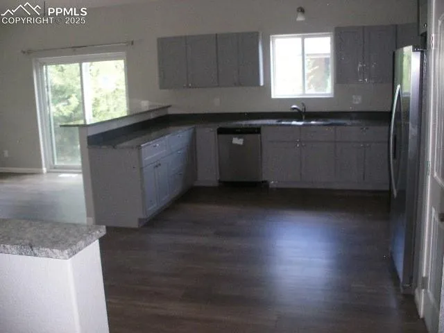 a kitchen with stainless steel appliances granite countertop a sink a stove a refrigerator a center island and wooden floor