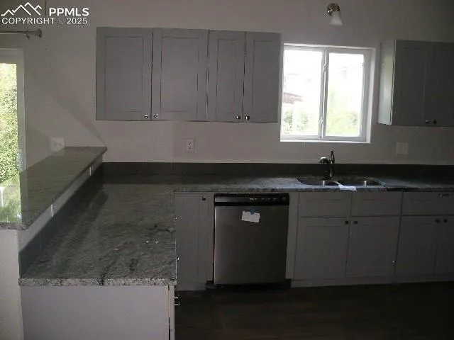 a kitchen with granite countertop white cabinets sink and window