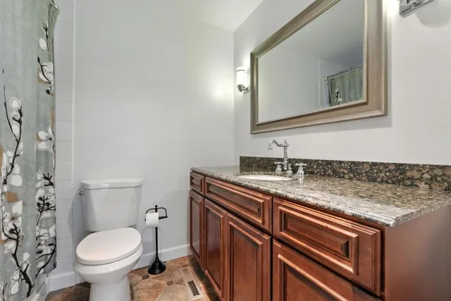 a bathroom with a granite countertop toilet sink and mirror