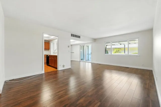 a view of an empty room with wooden floor and a window