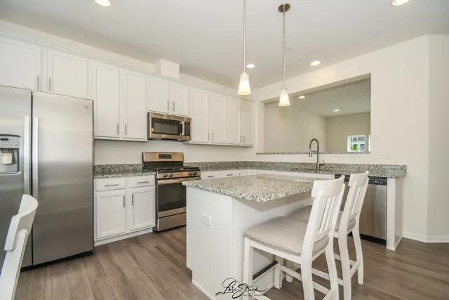 a kitchen with stainless steel appliances granite countertop a stove a refrigerator a microwave oven with a dining table and chairs