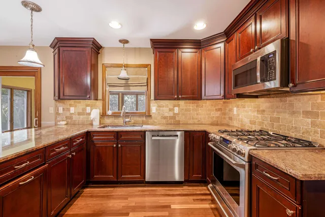 a kitchen with stainless steel appliances granite countertop wooden cabinets stove top oven and sink