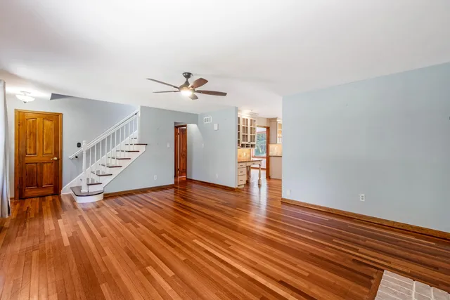 a view of an empty room with wooden floor and stairs