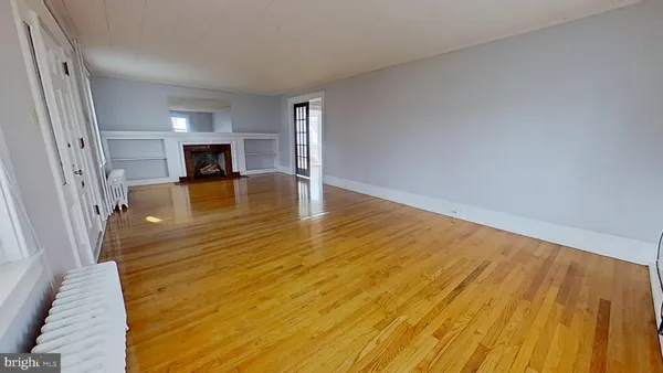 a view of an empty room with window and wooden floor