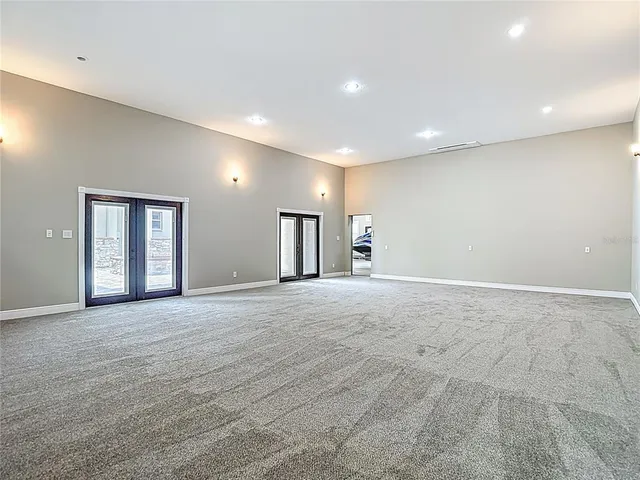a view of an empty room with window and chandelier fan