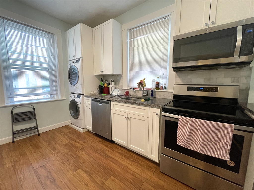 a kitchen with stainless steel appliances a stove a sink a microwave cabinets and a wooden floor
