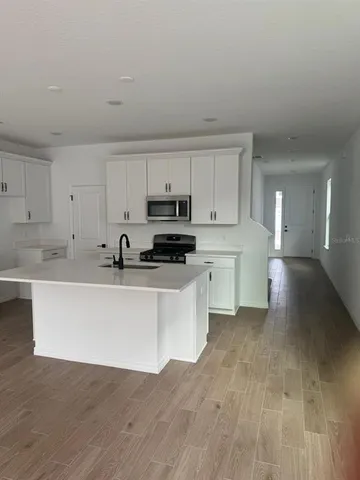 a kitchen with stainless steel appliances white cabinets and wooden floor