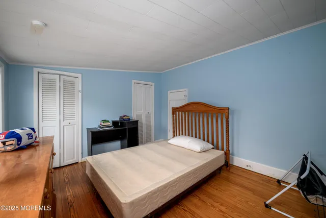 a bed sitting in a bedroom next to a window with wooden floor
