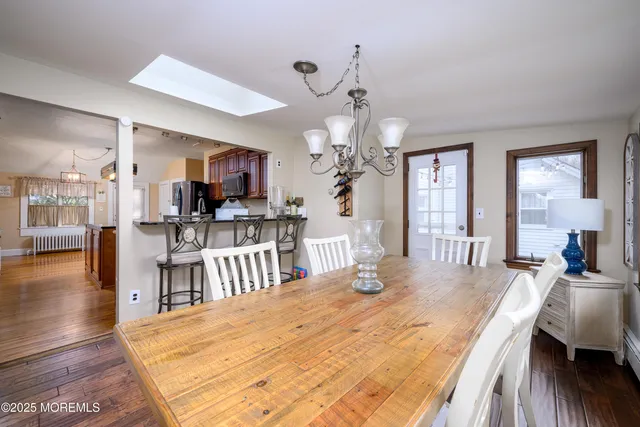 a view of a dining room and livingroom with furniture wooden floor a chandelier