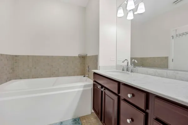 a bathroom with a tub sink and mirror
