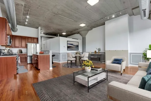 a living room with furniture kitchen view and a wooden floor