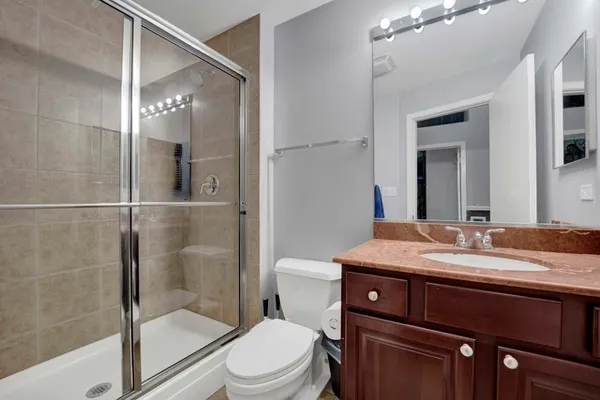 a bathroom with a granite countertop sink toilet a mirror and shower