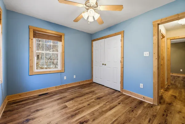 a view of an empty room with window and chandelier fan