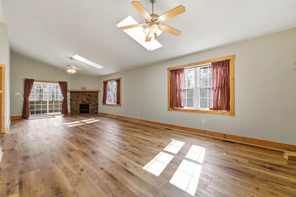a view of an empty room with window and wooden floor