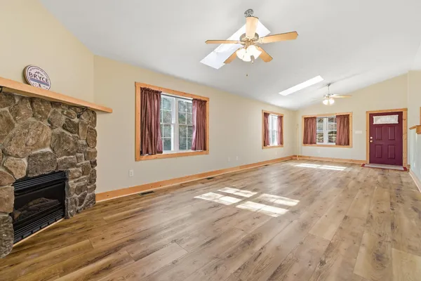a view of an empty room with window and wooden floor