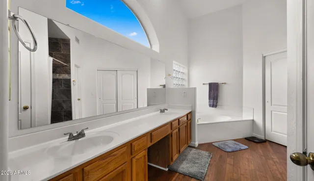 a spacious bathroom with a double vanity sink a mirror and a bathtub