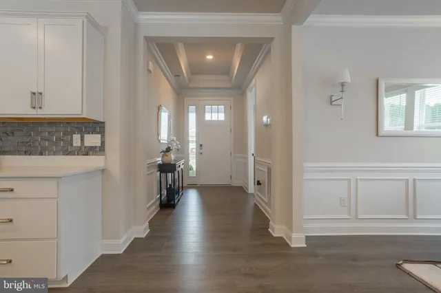 a view of a hallway with wooden floor windows and a living room